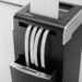 Modern cross-cut office shredder with paper being fed into throat opening and waste bin visible below