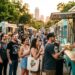 Small Austin food brand owner serving loyal local customers at a busy outdoor Texas farmers market during summer
