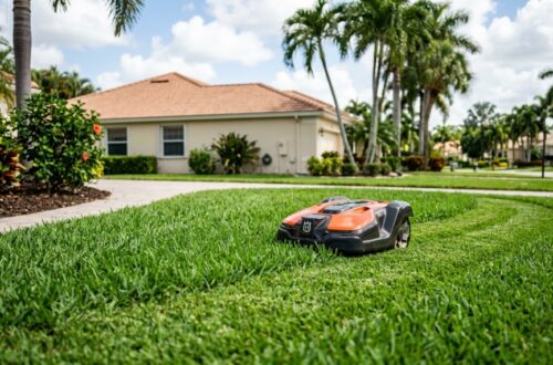 Robotic lawn mower cutting green grass in a sunny Florida suburban yard.